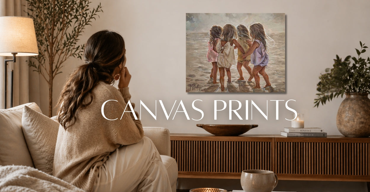 woman sitting in a living room looking at her canvas prit from house of maria, its a beach scene with 4 girls