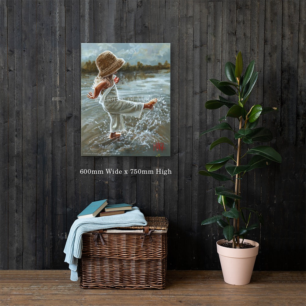 Lost in the Moment — a little girl in a straw hat splashing barefoot in the water by Maria Magdalena Oosthuizen, 600 x 750mm canvas print on a dark wood wall | canvas print wall art | House of Maria