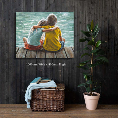 Canvas print of two children hugging on a dock with dimensions displayed, placed on a wooden floor against a dark wooden wall.