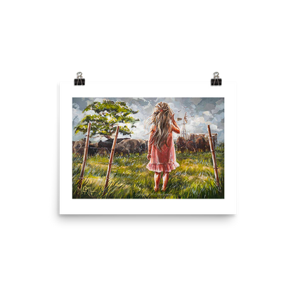 An artistic print featuring a girl in a pink dress with a cow in the background, set against a grassy field with a windmill in the distance.